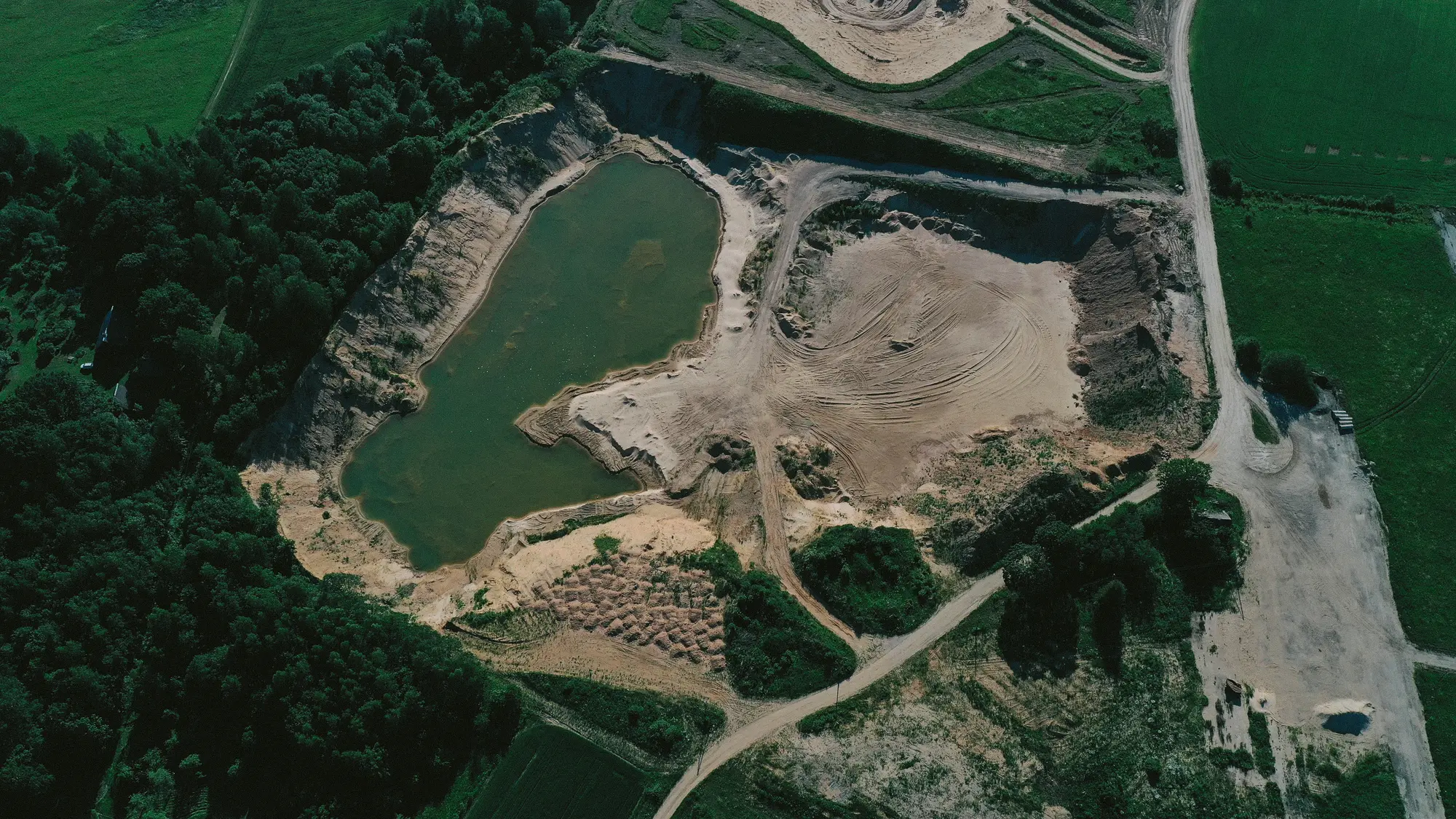 Vista aérea de una cantera con una laguna rodeada de bosque